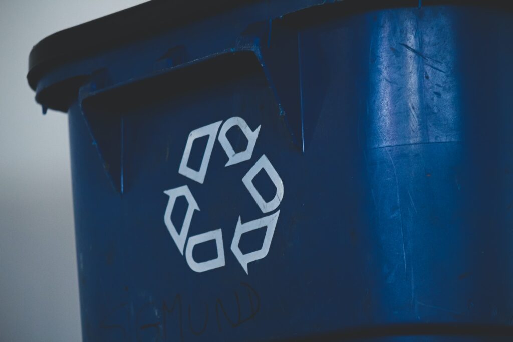 Side of recycling bin with the recycling logo on it in white